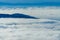 Generic beautiful landscape with blue hills rising from the white sea of clouds