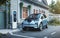 Generic electric vehicle EV hybrid car is being charged from a wallbox near a contemporary modern residential building