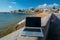 Generic notebook laptop on sunny deserted sandy beach background