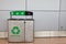 Generic recycling receptacle with trash section against long gray wall with Ind Recycles slogan