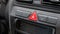 Generic red triangle emergency stop hazard lights button on a car dashboard, car interior object detail closeup, nobody. Vehicle