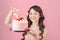 Generous woman holding birthday cake front pink background