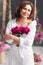 a gentle attractive middle-aged woman in white clothes with a bouquet of peonies