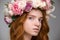 Gentle beautiful girl with red hair in wreath of roses