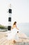 A gentle bride in a dress with an open back is spinning on the pier under the lighthouse in the Bay of Kotor