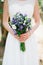 Gentle bride holding a wedding bouquet with blue and white asters, lisiantuses and lavender in her hands, close-up