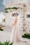 A gentle bride in a lace veil stands near a white brick house in the old town of Perast