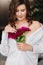 A gentle brunette woman in white clothes with a bouquet of peonies.