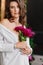 A gentle brunette woman in white clothes with a bouquet of peonies.