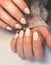 Gentle camouflage gel nail polish with white marble. Hands with a professional manicure in a sweater.