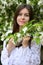 Gentle female portrait in the blooming garden in the white dress.