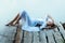 Gentle girl in white dress lying on a wooden pier.