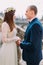 Gentle groom holding hands with his pretty bride while both stand on antique stone stairs. Close up