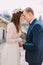 Gentle groom holding hands and touching by foreheads with his pretty bride while both stand on antique stone stairs