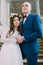 Gentle groom holding his charming bride while both stand on antique stone stairs. Low angle shot