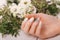 Gentle neat manicure on female hands on flowers background. Nail design