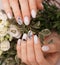 Gentle neat manicure on female hands on flowers background. Nail design