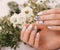 Gentle neat manicure on female hands on flowers background. Nail design