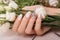 Gentle neat manicure on female hands on flowers background. Nail design