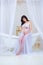Gentle pregnancy. Beautiful pregnant in light white dress with orchids