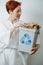 Gentle short-haired woman holding a small recycle bin stuffed with paper