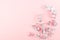 Gentle simple decorative border of silver branches with copy space on pastel pink background, top view.