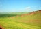 A gentle slope of a high hill with sheer stone cliffs at the top and a fertile pasture at the foot