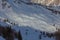 Gentle snow-covered slope with small isolated hut at sunset