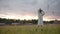 Gentle woman in white dress walking in rural field near village