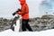 Gentoo penguin walking along beach on Danco Island, Antarctica, photographer in red coat in background looking the wrong way