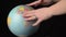 Geographical Globe is Twisted Around its Axis by a Female Hand