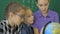 Geography lesson. Schoolmates are studying the globe on the background of a school board