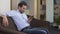 Geography teacher sitting on sofa and scrolling on smartphone, technologies