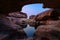 Geological hole cave in large rocky rapids and pond reflection in the evening