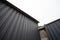 Geometric industrial dark composition of a concrete gray wall and an iron corrugated roof