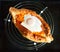 Georgian national dish Adjarian khachapuri on a black background.