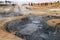 Geothermal field Namaskard, Iceland. People in desolate landscape with mud volcano and hot steam.