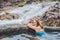 Geothermal spa. Woman relaxing in hot spring pool against the background of a waterfall