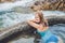 Geothermal spa. Woman relaxing in hot spring pool against the background of a waterfall