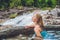 Geothermal spa. Woman relaxing in hot spring pool against the background of a waterfall