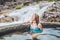 Geothermal spa. Woman relaxing in hot spring pool against the background of a waterfall