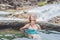 Geothermal spa. Woman relaxing in hot spring pool against the background of a waterfall