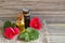 Geranium essential oil in a glass bottle with flowers and leaves of the geraniums plant on wooden table.