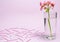 A geranium flower of coral color stands in a glass beaker with clear water against a background of a delicate coral color