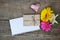 Gerberas flowers with two hearts, envelope and white paper on wood