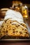 German Christmas powdered stollen with raisins, nuts, candied fruits, sliced,festive table setting, lit candle