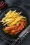 German currywurst Sausages with French fries on a plate. Black background. Top view