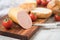 German fine veal liver sausage spread on crispy bread roll bun, with butter, tomatoes, wooden board, kitchen towel and light