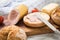 German fine veal liver sausage spread on crispy bread roll bun, with butter, tomatoes, wooden board, kitchen towel and light