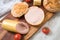 German fine veal liver sausage spread on crispy bread roll bun, with butter, tomatoes, wooden board, kitchen towel and light